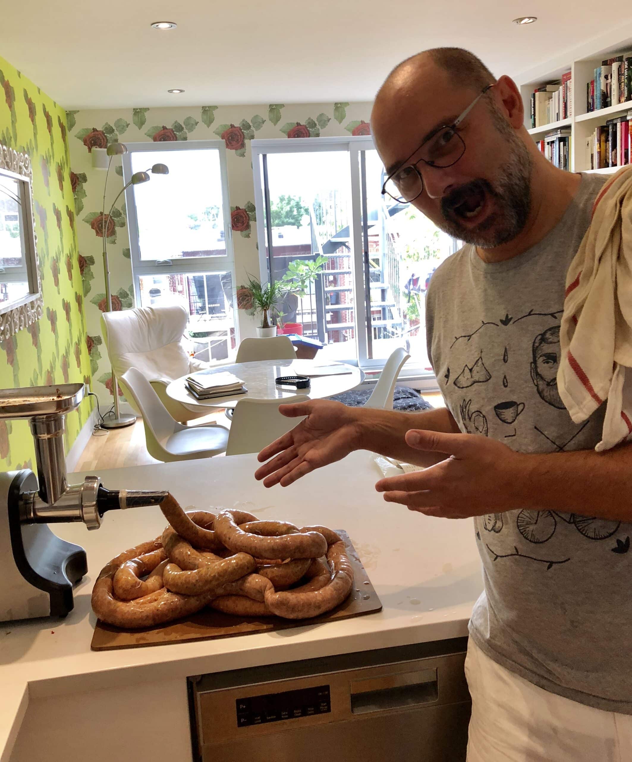 Un homme présente les saucisses fraîchement embossées, sur le comptoir.