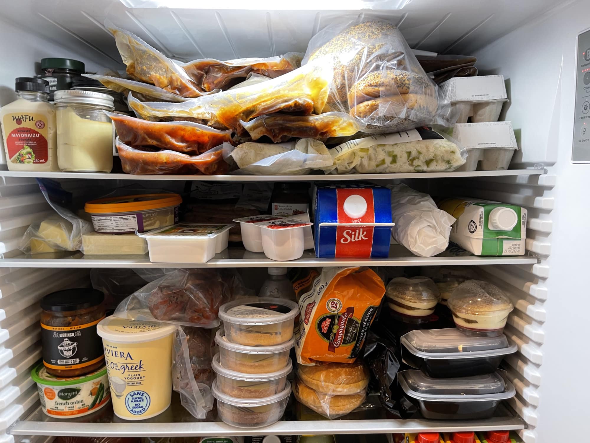 Un réfrigérateur rempli de contenants et de plats préparés.