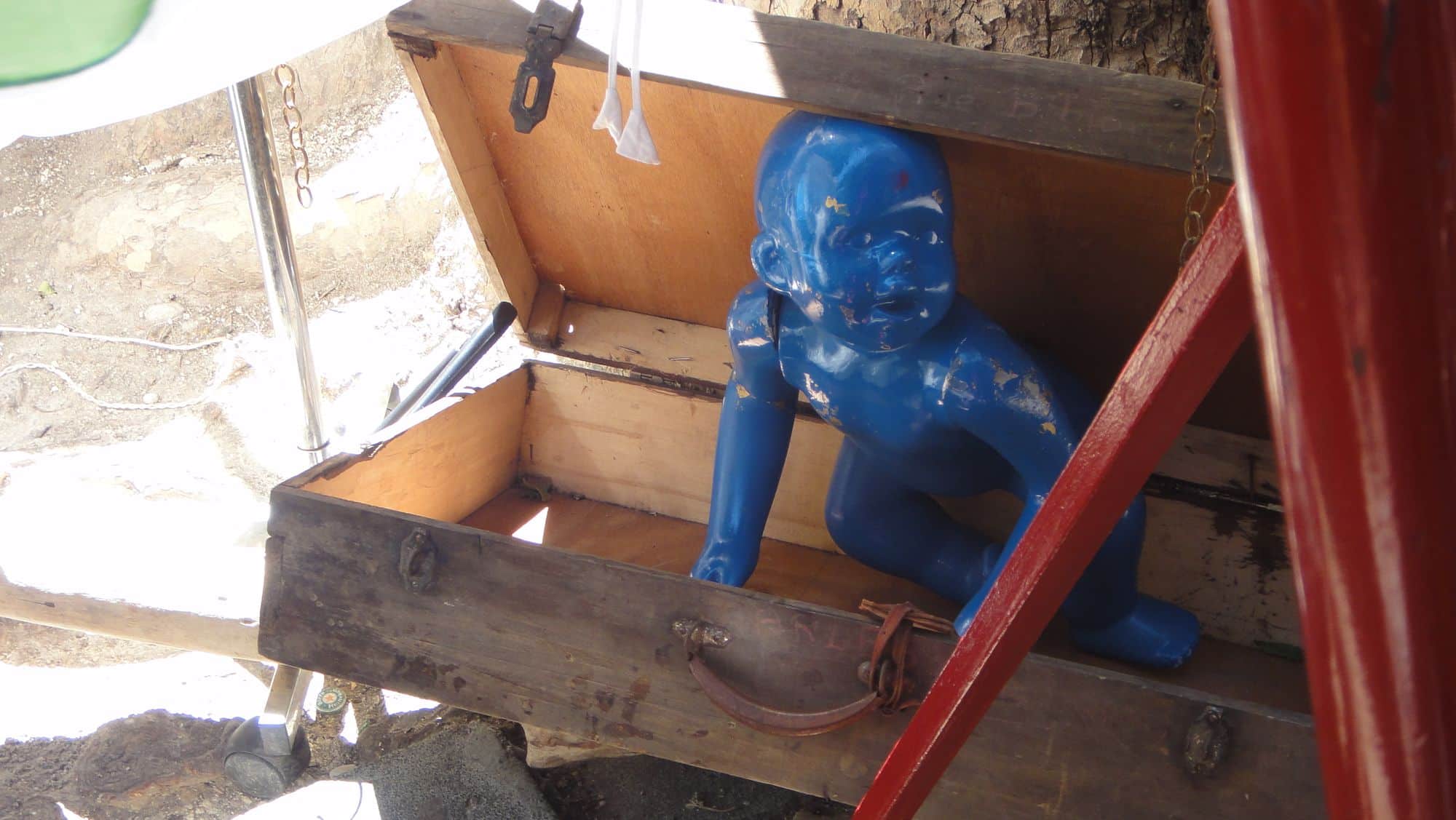 Une figure peinte en bleu, installée dans un coffre de bois.
