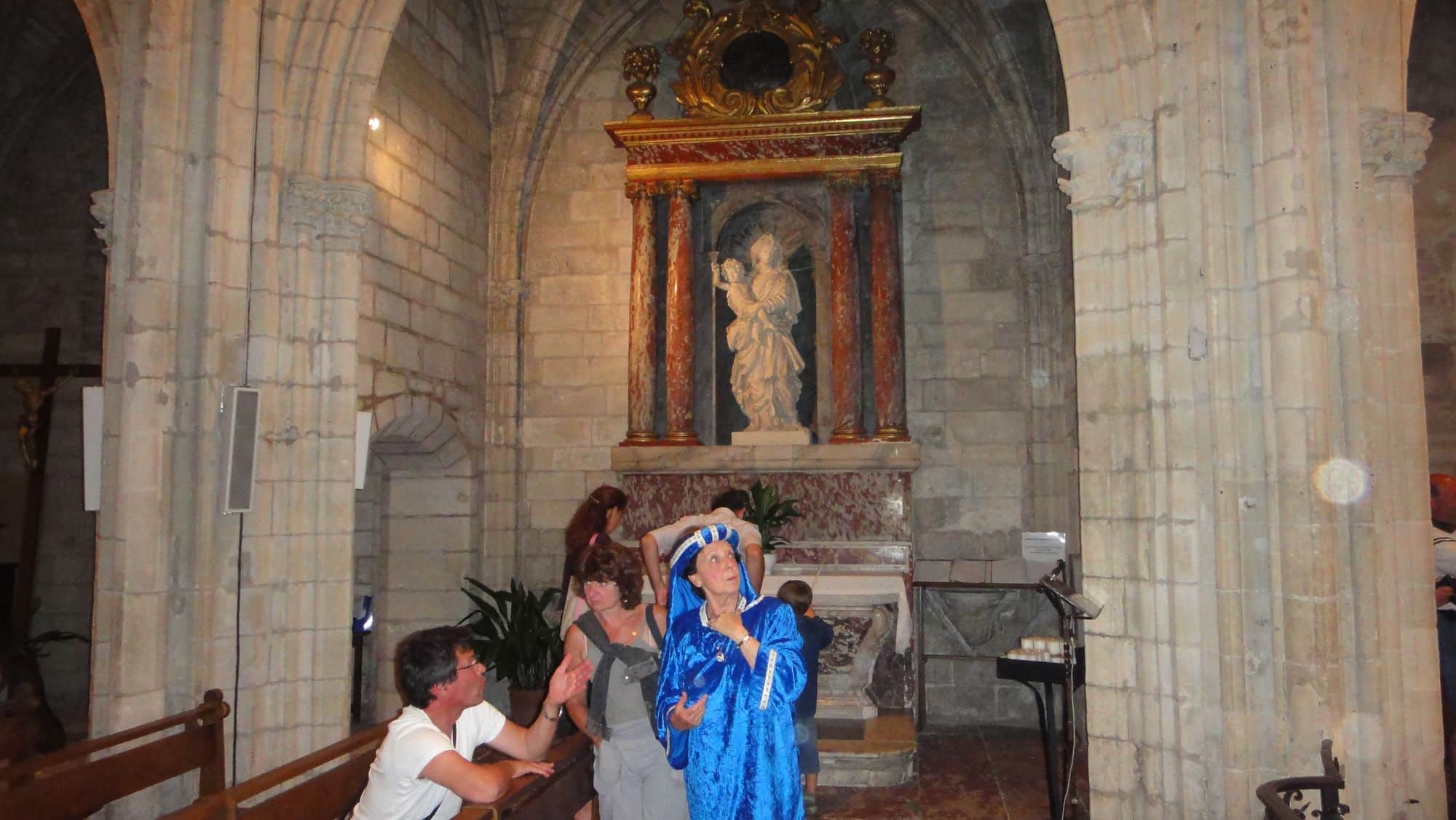 Dans l'église, une comédienne en costume bleu entourée d'enfants.