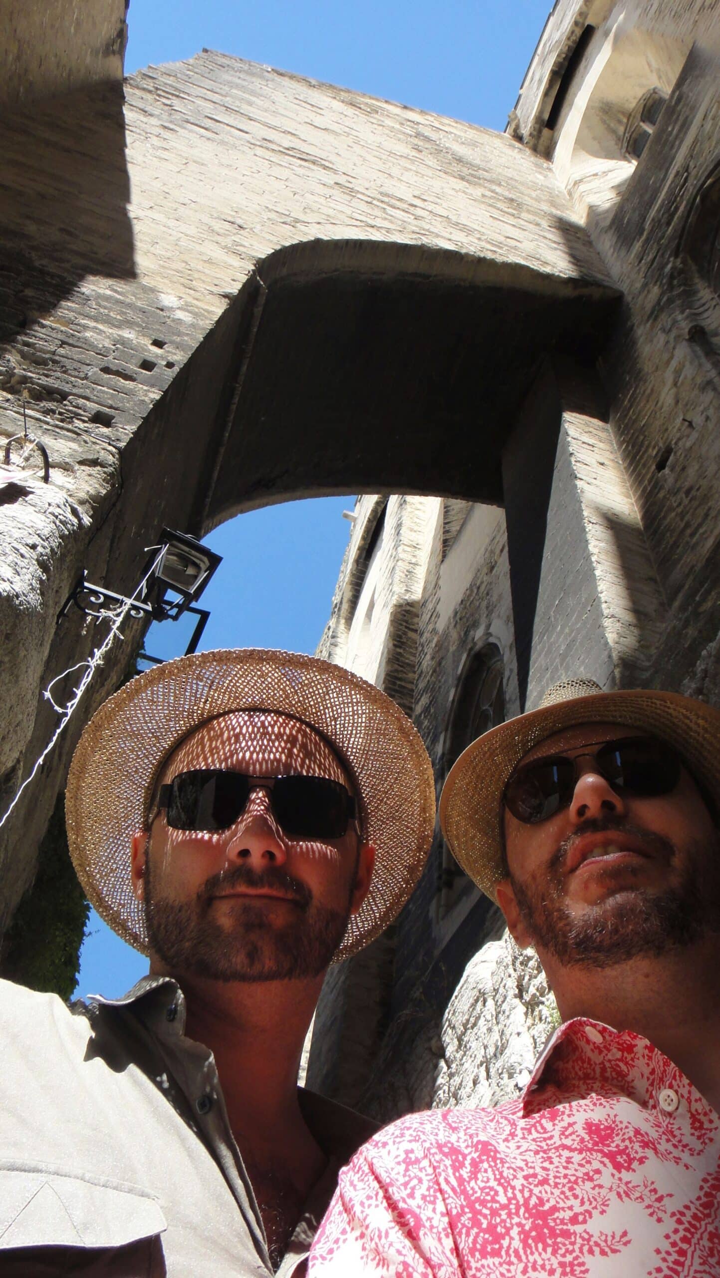 Deux hommes en chapeau de paille sous une arche de pierre.