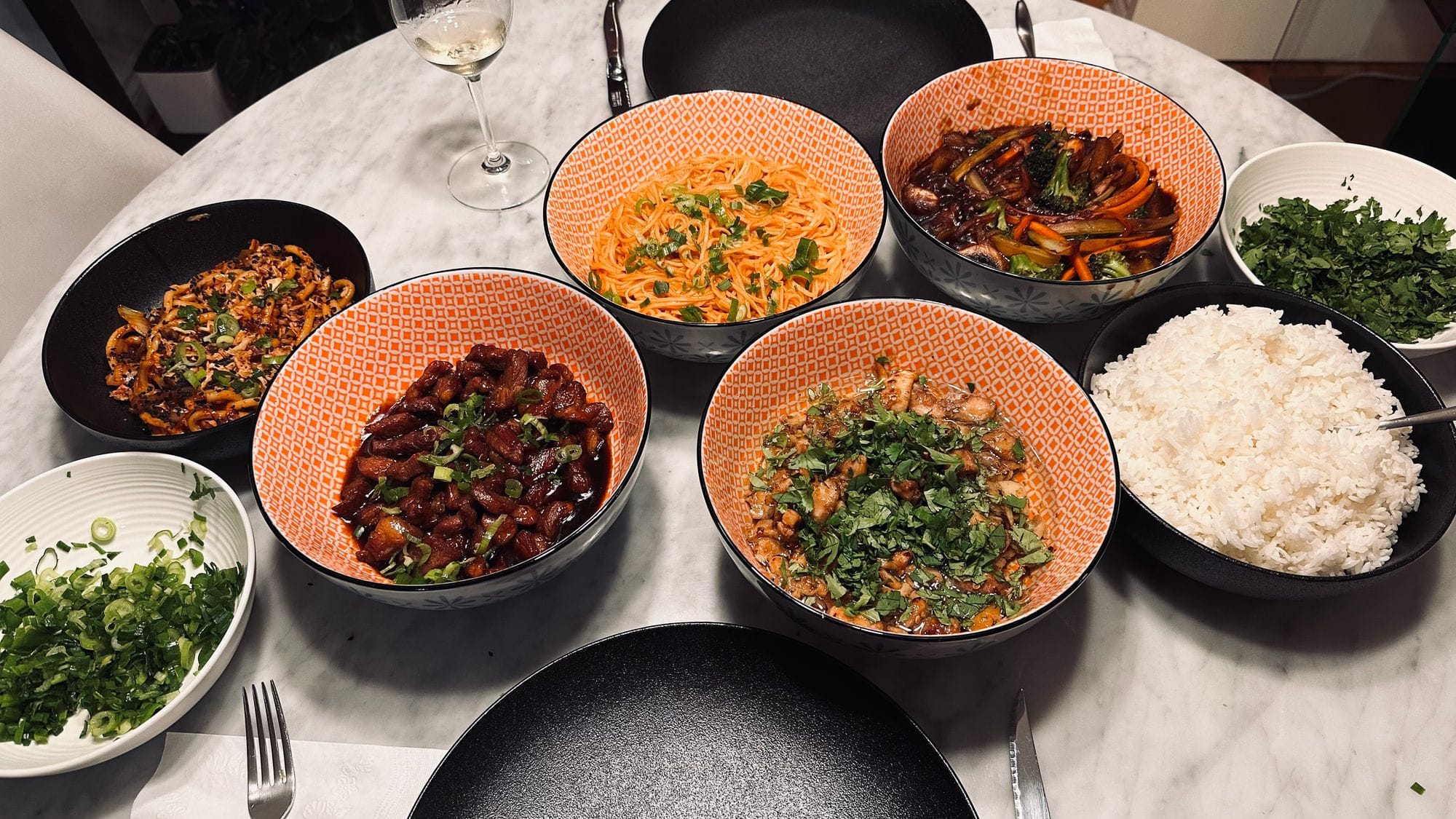 Une tablée de bols garnis, riz et herbes fraîches au centre.