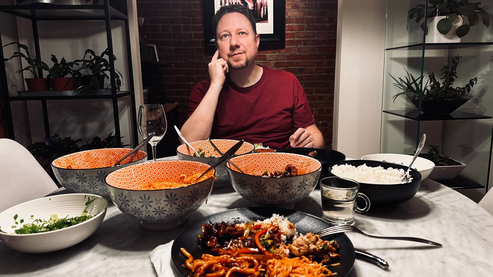 Un homme attablé devant plusieurs plats asiatiques partagés.
