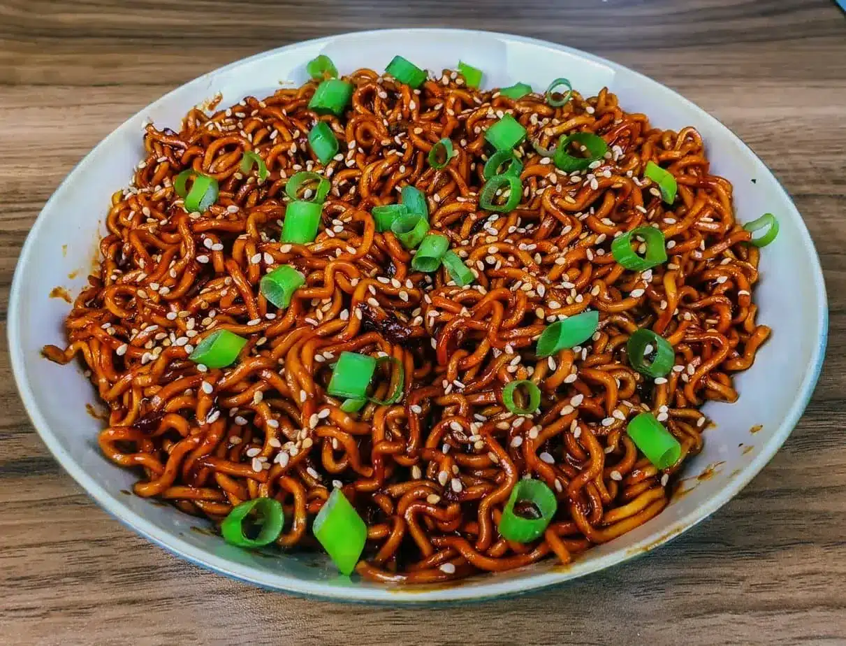 Un grand plat de nouilles sautées parsemées d'oignons verts.