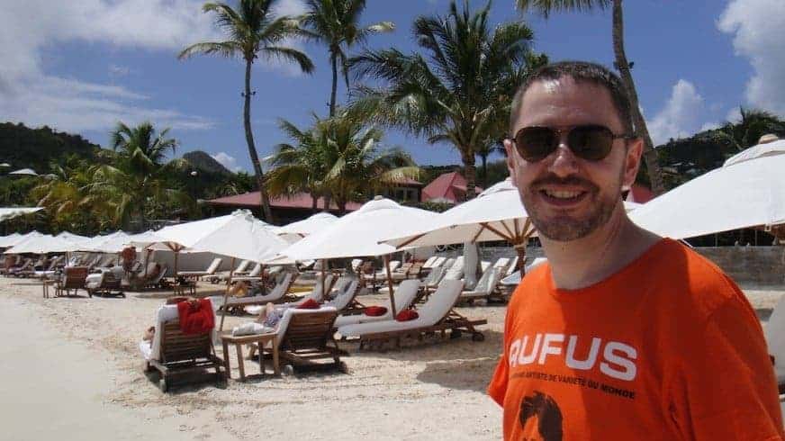Un homme en t-shirt orange devant les transats de la plage.