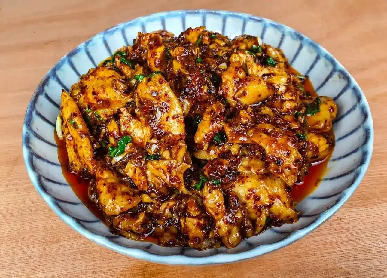 Des morceaux de poulet en sauce épicée dans un plat creux.