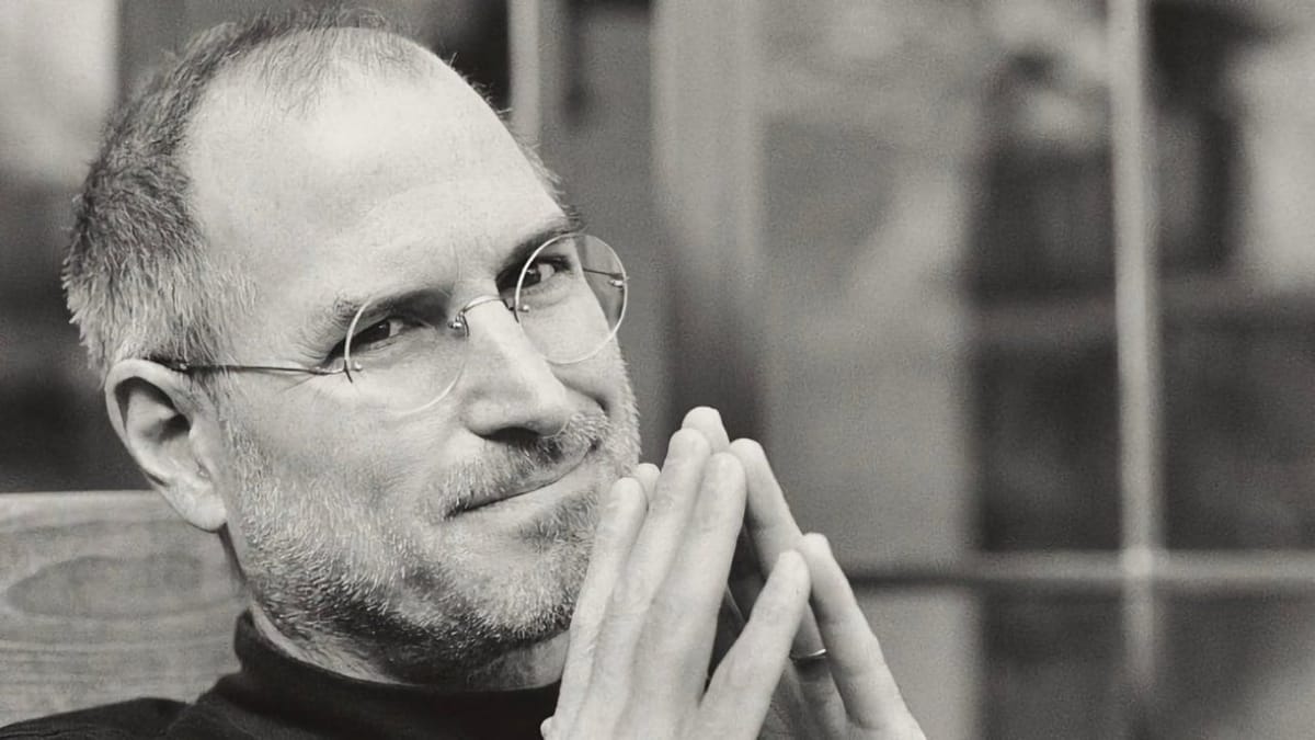 Portrait en noir et blanc de Steve Jobs, les mains jointes.