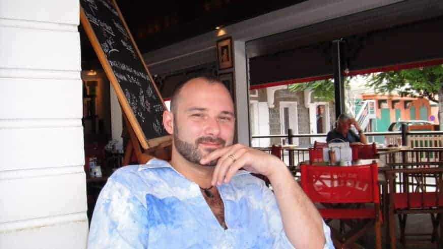 Un homme accoudé au comptoir d'un restaurant ouvert sur la rue.