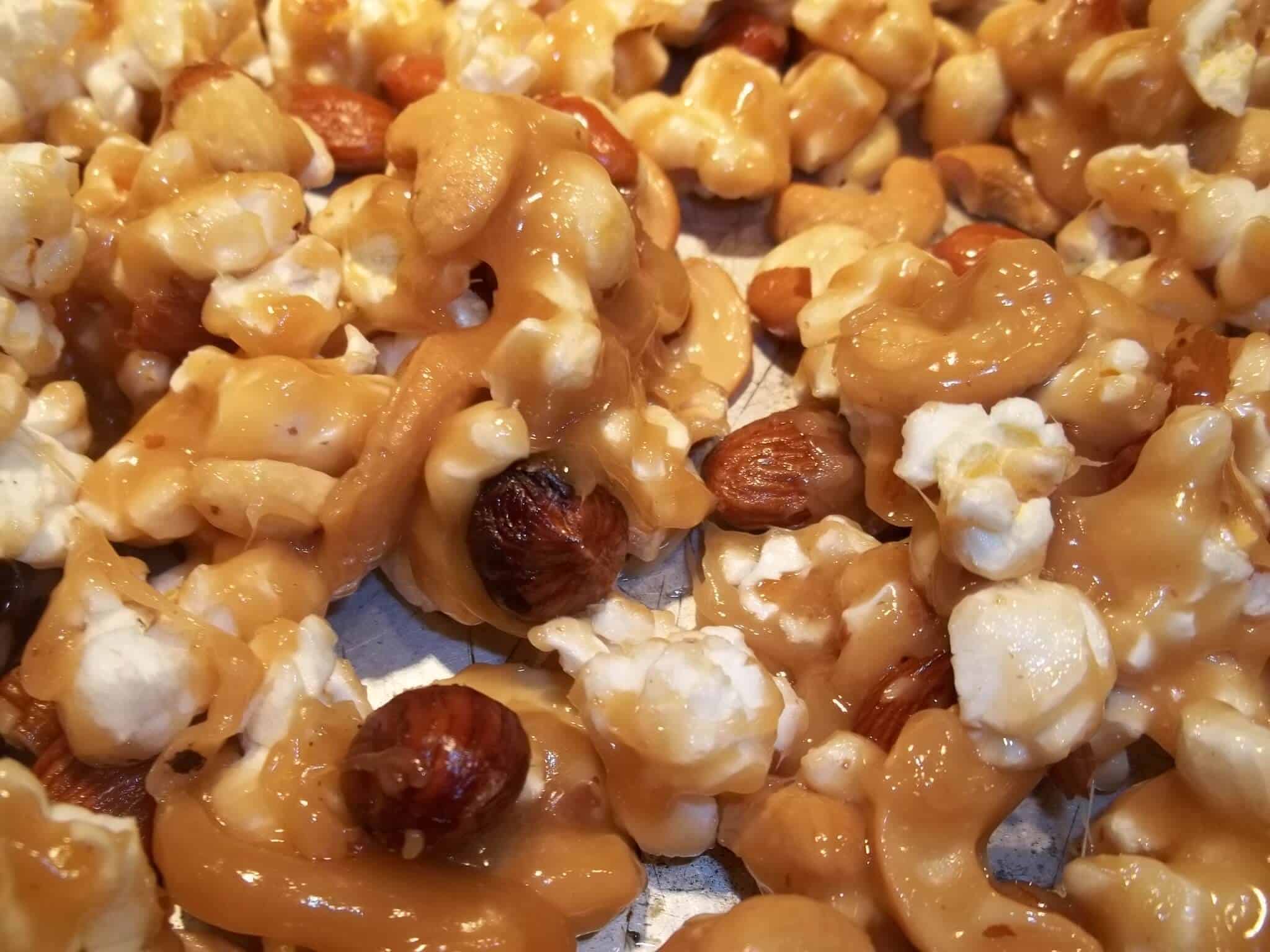 Gros plan sur du maïs soufflé enrobé de caramel et mêlé de noix.