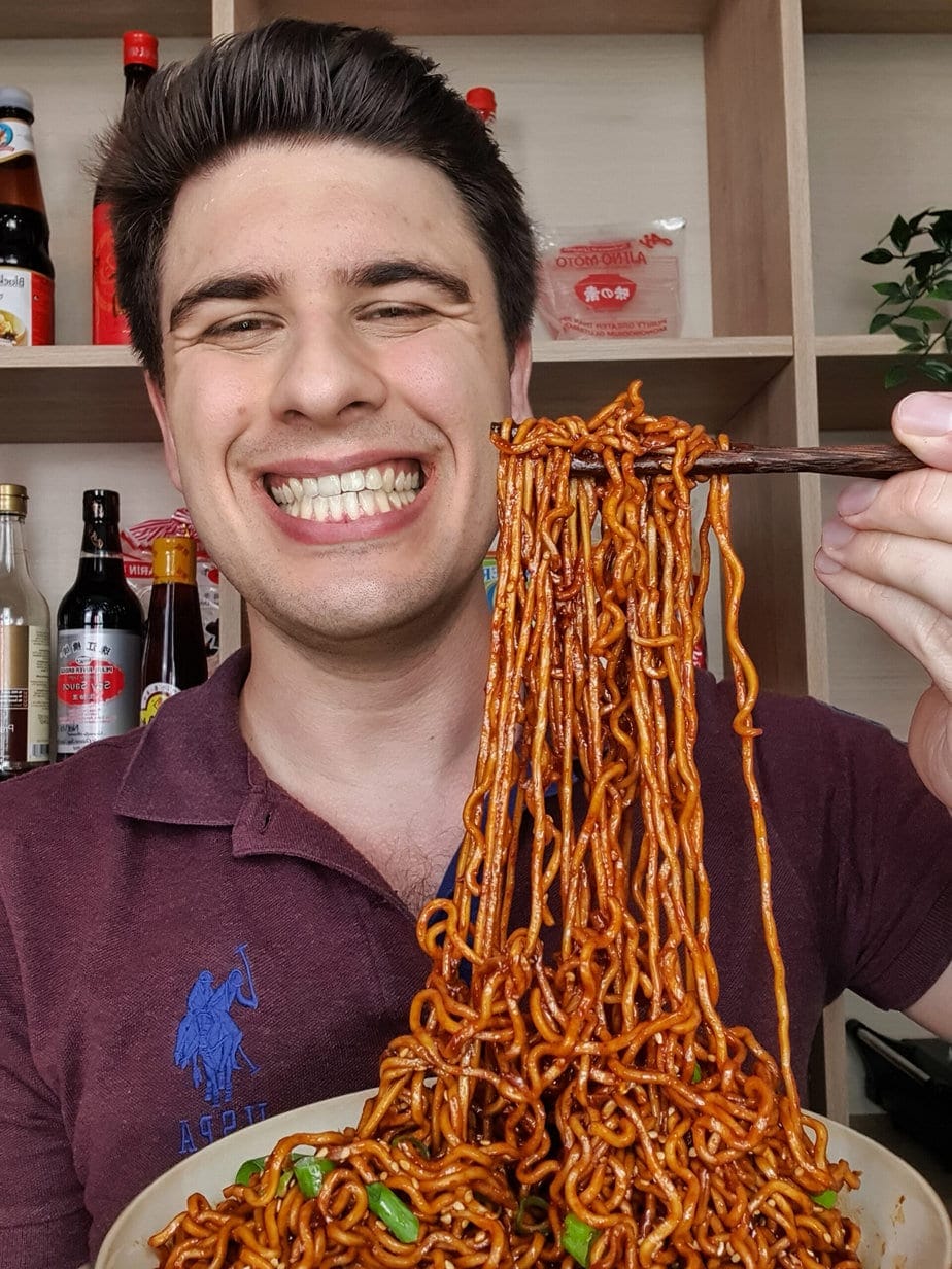 Marc Winer soulève une portion de nouilles avec ses baguettes, devant ses sauces.